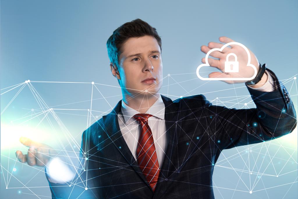 schöner Geschäftsmann im Anzug zeigt auf Netzwerk und Lock-in-Cloud-Illustration vor blauem Hintergrund - Foto, Bild