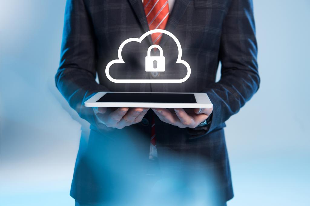 vista parcial del hombre de negocios sosteniendo tableta digital con bloqueo e iconos de la nube sobre fondo azul
 - Foto, imagen