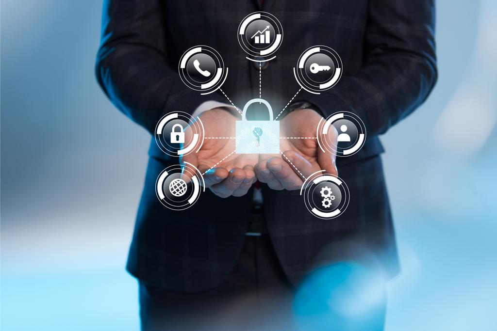 частковий вид на бізнесмена з простягнутими руками та піктограмами інтернет-безпеки зверху на синьому фоні
 - Фото, зображення