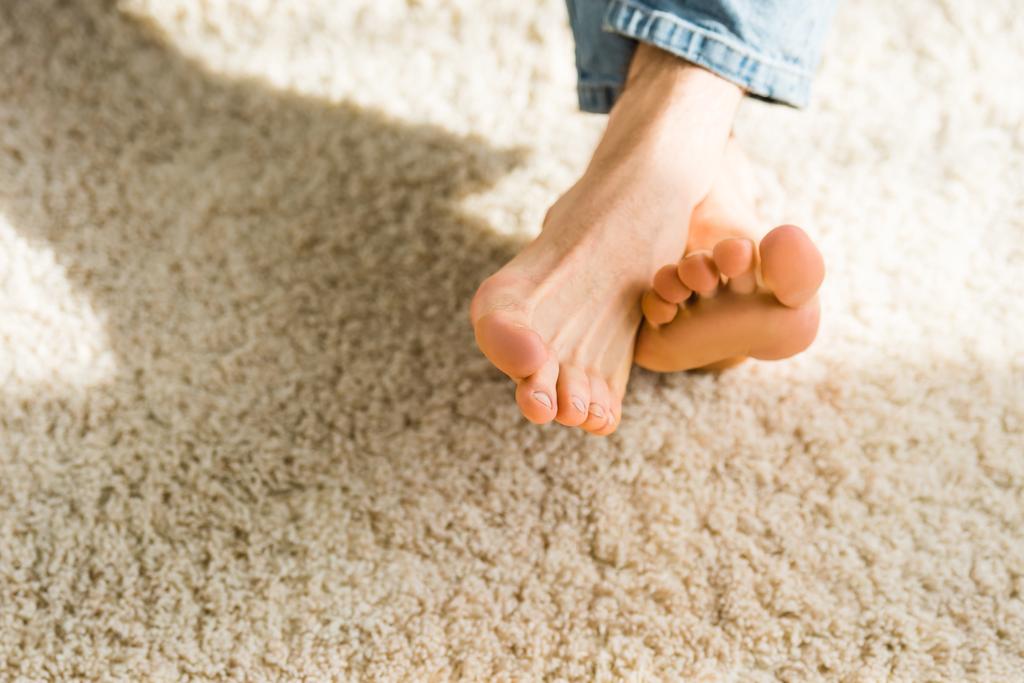 vista recortada de los pies masculinos en alfombra beige
 - Foto, Imagen