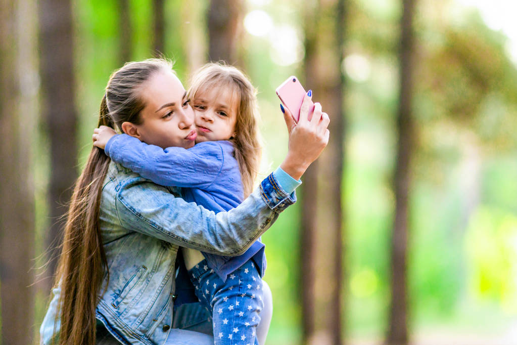 Pozytywne, że matka i córka zrobić selfie na spacer w lesie. Prowokacyjne nastroju. Słoneczny dzień lata. - Zdjęcie, obraz