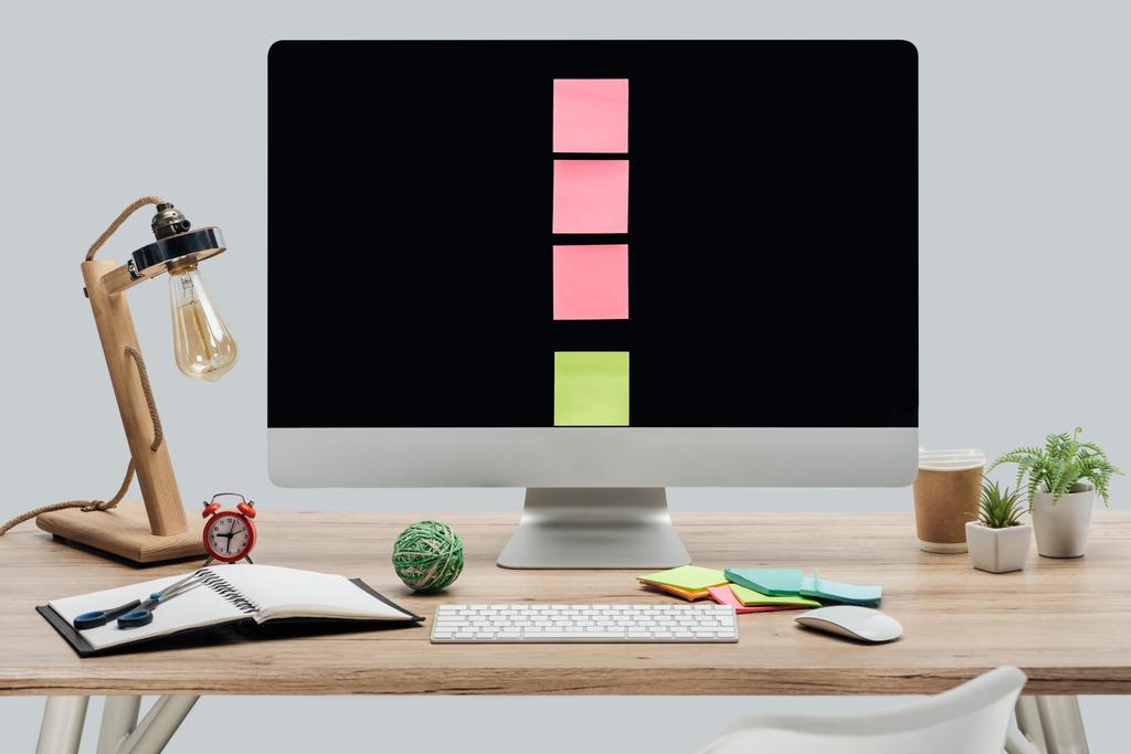 modern workplace with computer monitor with sticky notes and stationery at wooden desk isolated on grey - Photo, Image