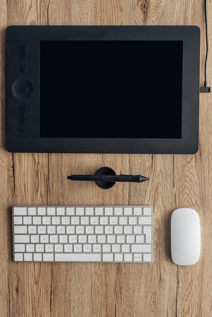 bovenaanzicht van grafisch tablet, grafische pen, draadloos toetsenbord en computermuis op houten tafel - Foto, afbeelding