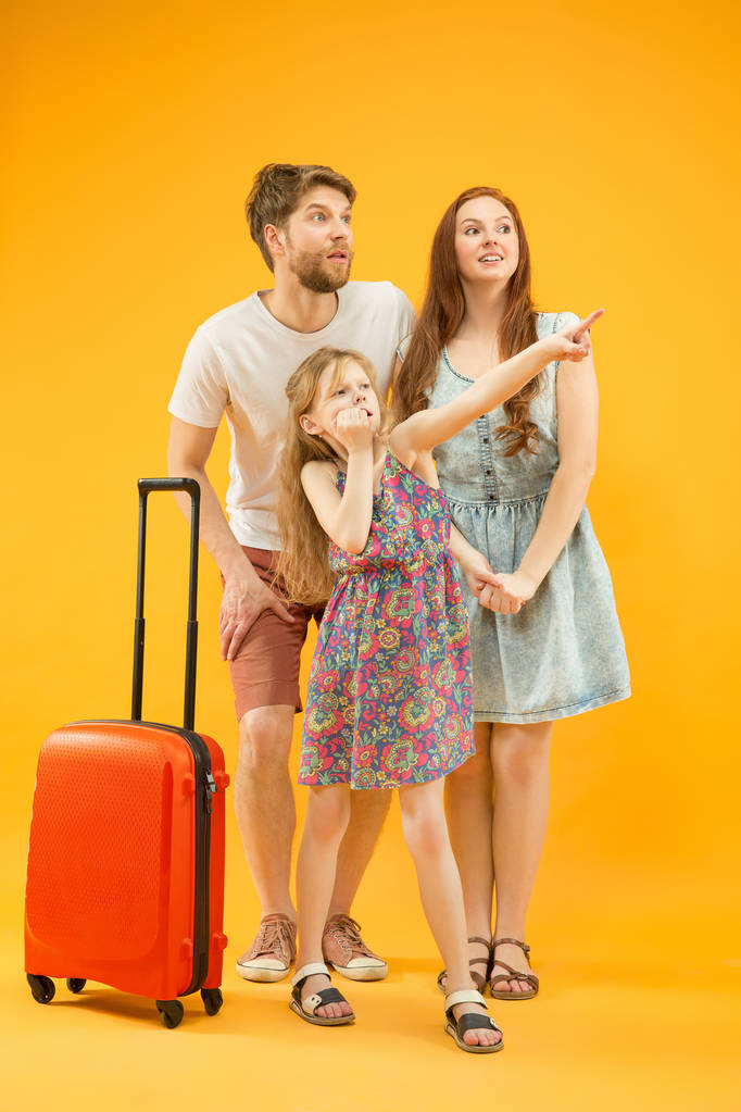 Ευτυχισμένος γονέας με κόρη και βαλίτσα στο στούντιο που απομονώνονται σε κίτρινο φόντο - Φωτογραφία, εικόνα