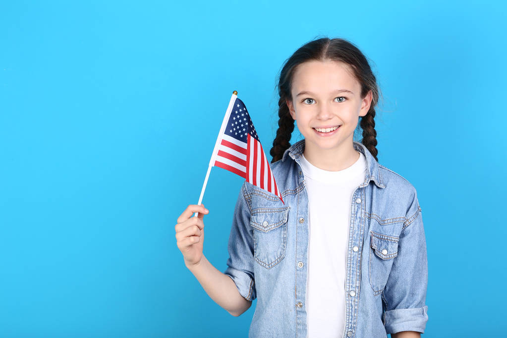 Jong meisje die houdt van een Amerikaanse vlag op blauwe achtergrond - Foto, afbeelding