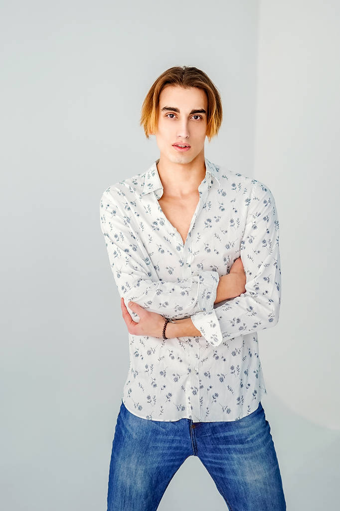 Retrato de moda de hombre joven con camisa blanca posa sobre pared gris
 - Foto, Imagen