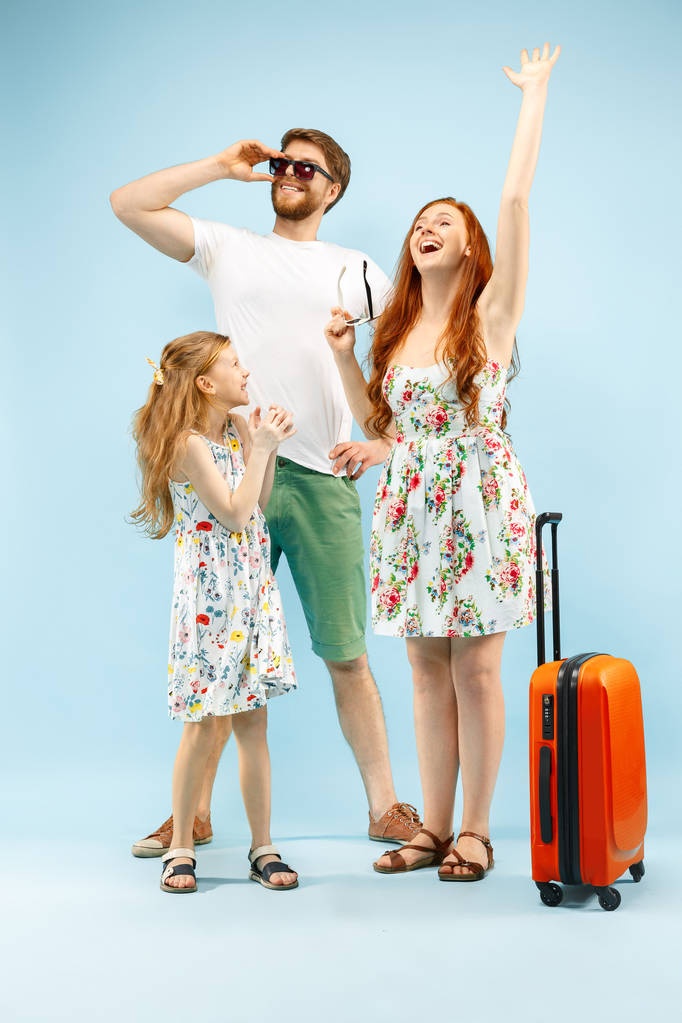 Szczęśliwy rodzic z córka i walizkę w studio samodzielnie na niebieskim tle - Zdjęcie, obraz
