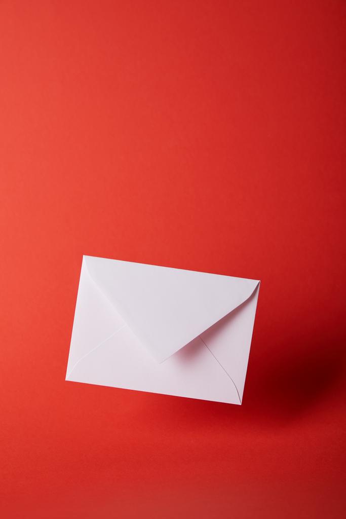 envelope branco e vazio no fundo vermelho brilhante com espaço de cópia
  - Foto, Imagem