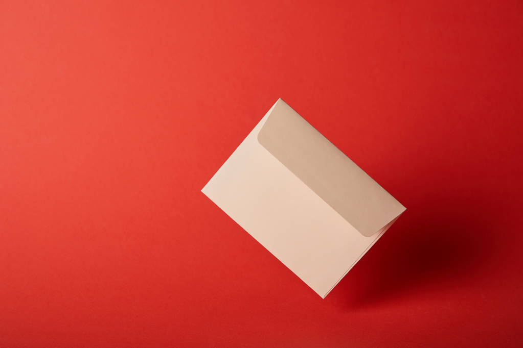 beige, blank and empty envelope on colorful red background with copy space  - Photo, Image