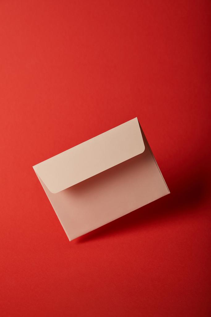 μπεζ, κενό και άδειο φάκελο στο πολύχρωμο λαμπερό κόκκινο φόντο και με αντίγραφο χώρου  - Φωτογραφία, εικόνα