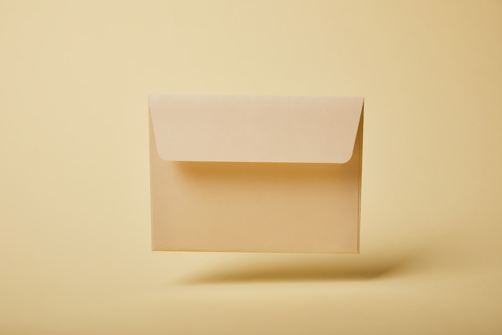 бежевый и пастельный конверт на желтом фоне с копировальным пространством
  - Фото, изображение