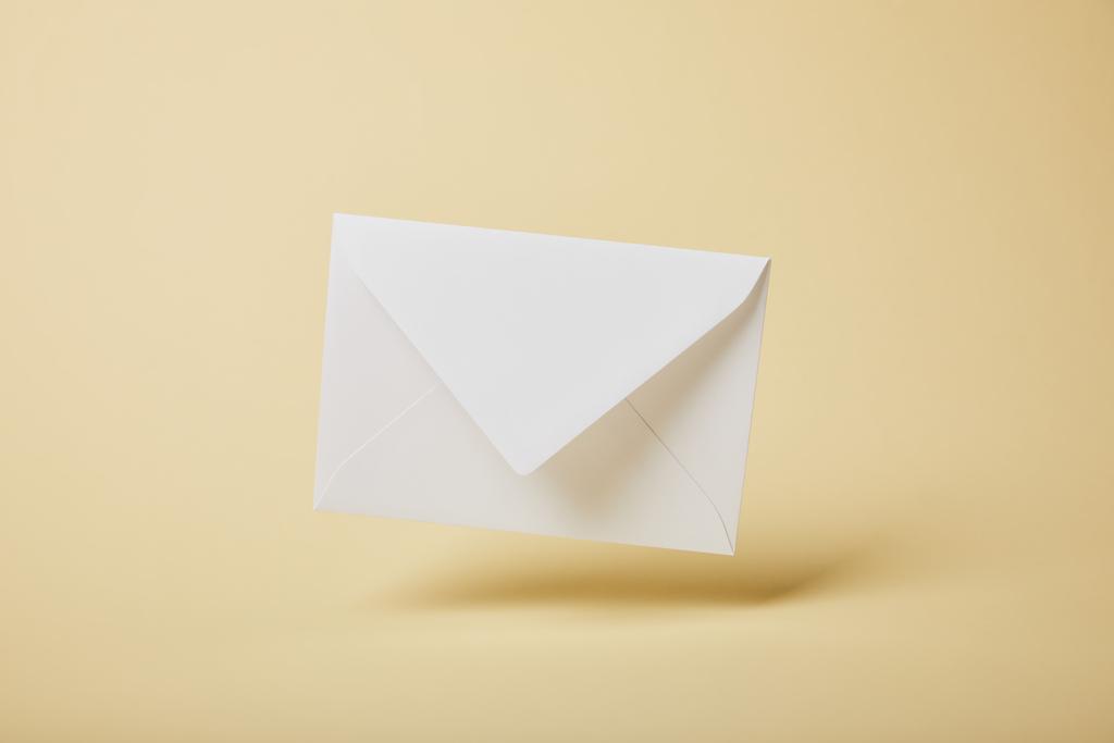 witte en lege envelop op gele achtergrond met kopie ruimte  - Foto, afbeelding