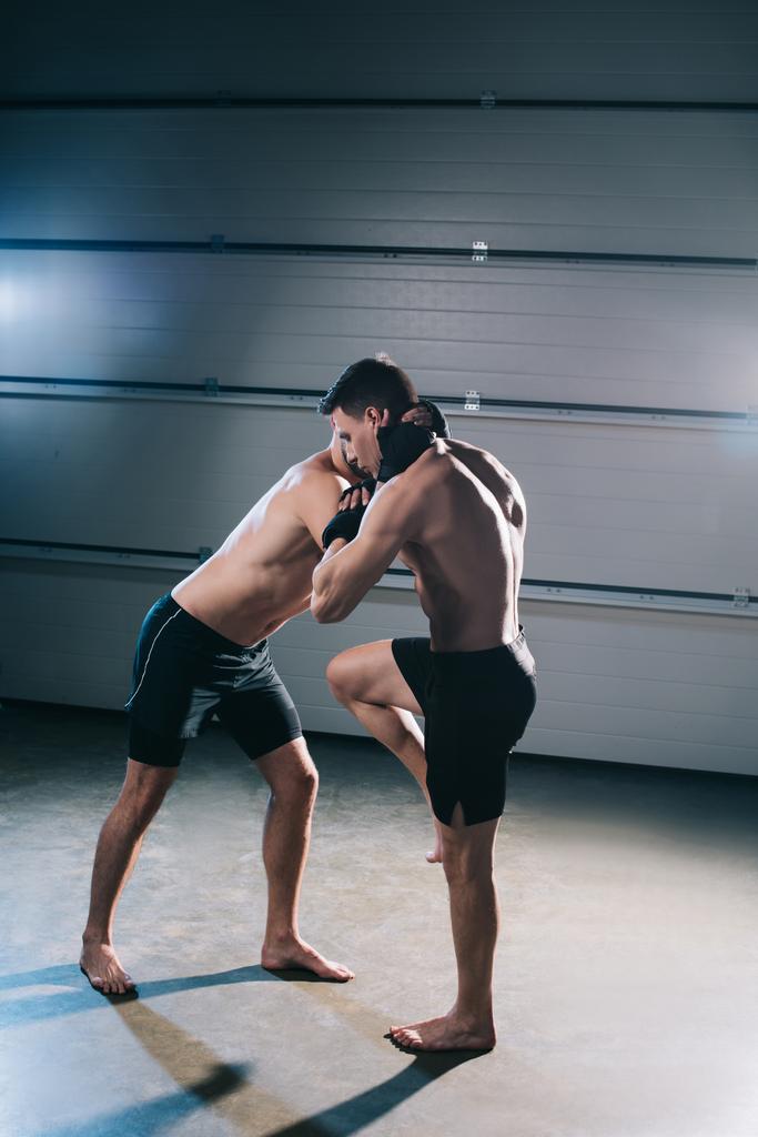 м'язистий босоніж винищувач, який штовхає суперника спорту з коліном
 - Фото, зображення