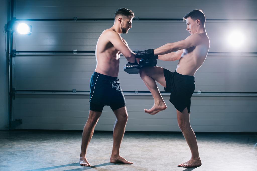lekkoatletycznego mięśni mma fighter praktykujących kick z innego sportowca podczas treningu - Zdjęcie, obraz