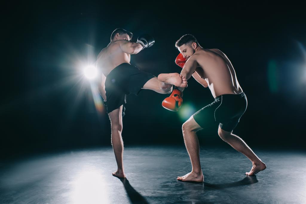 strong mma fighter kicking another sportsman with leg in arm - Photo, Image
