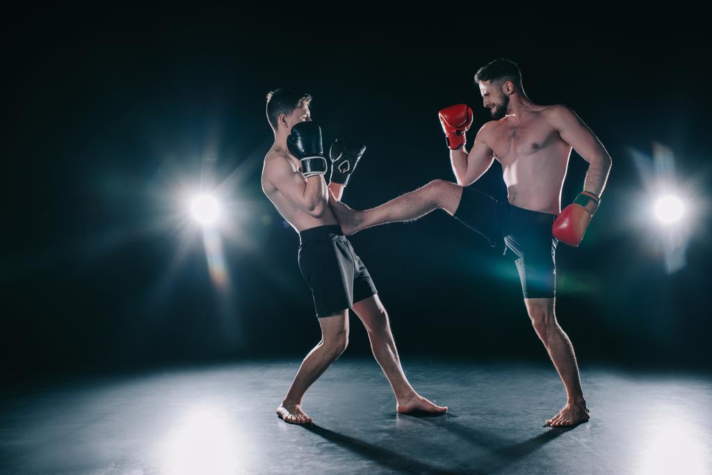 luchador mma muscular sin camisa en guantes de boxeo patadas otro en el torso
  - Foto, imagen