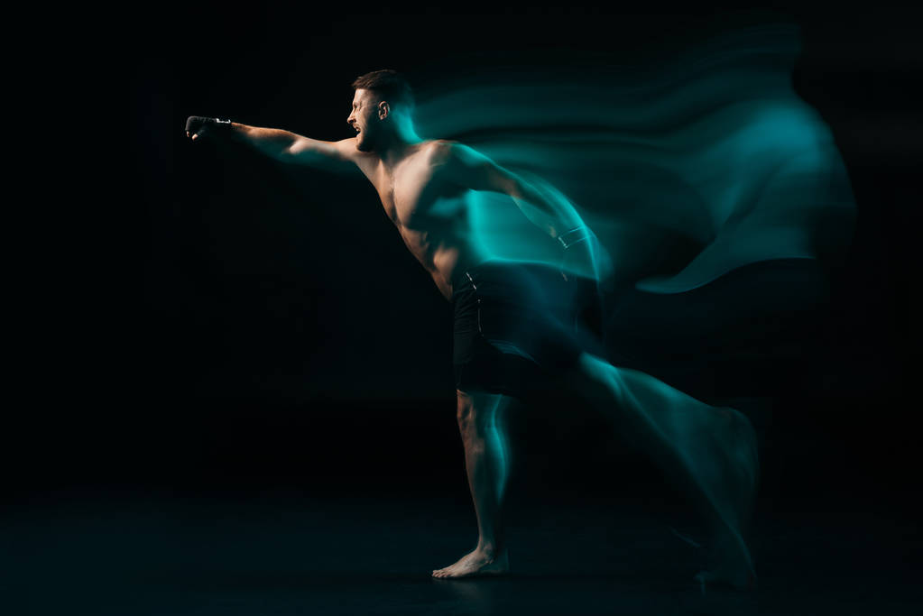 long exposure of green light and sporty muscular mma fighter doing punch - Photo, Image