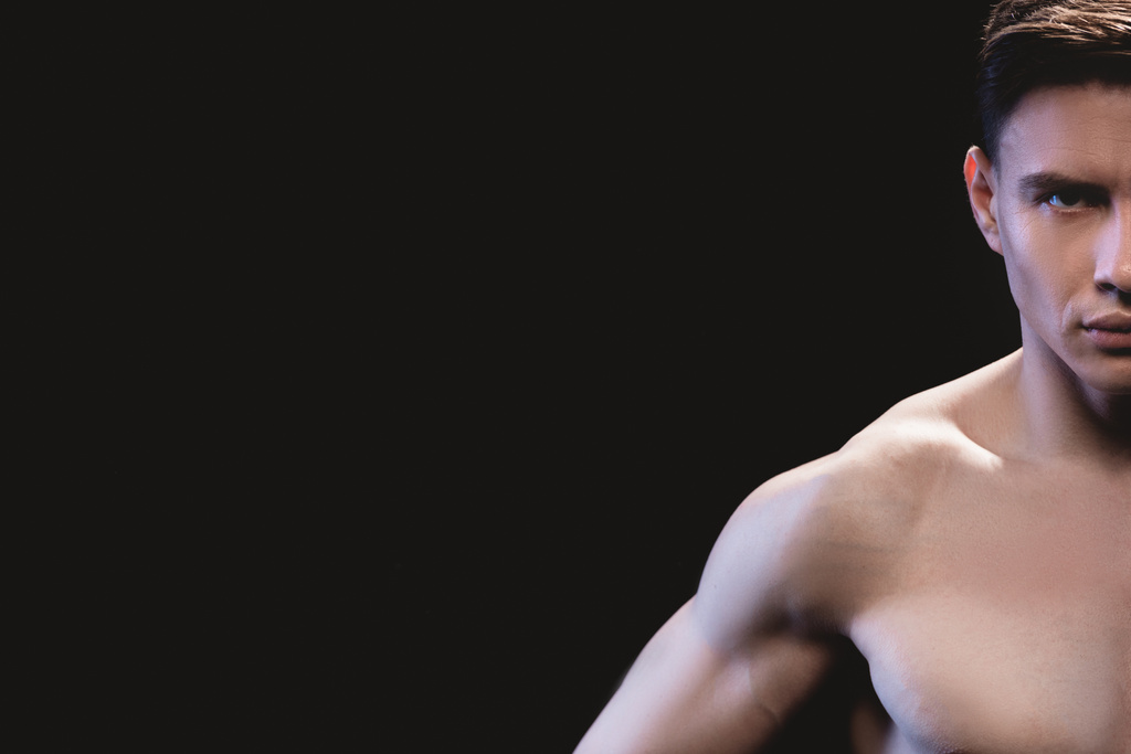 Teilbild eines gut aussehenden, muskulösen Sportlers, der isoliert auf schwarz in die Kamera blickt - Foto, Bild