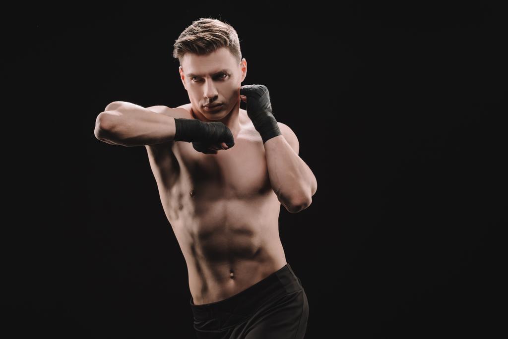 athletic muscular sportsman in bandages doing punch with elbow isolated on black - Photo, Image
