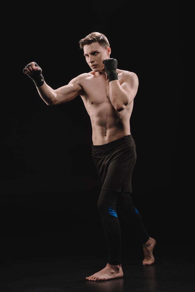 сильный босиком мускулистый спортсмен в бинтах делает удар по черному
 - Фото, изображение