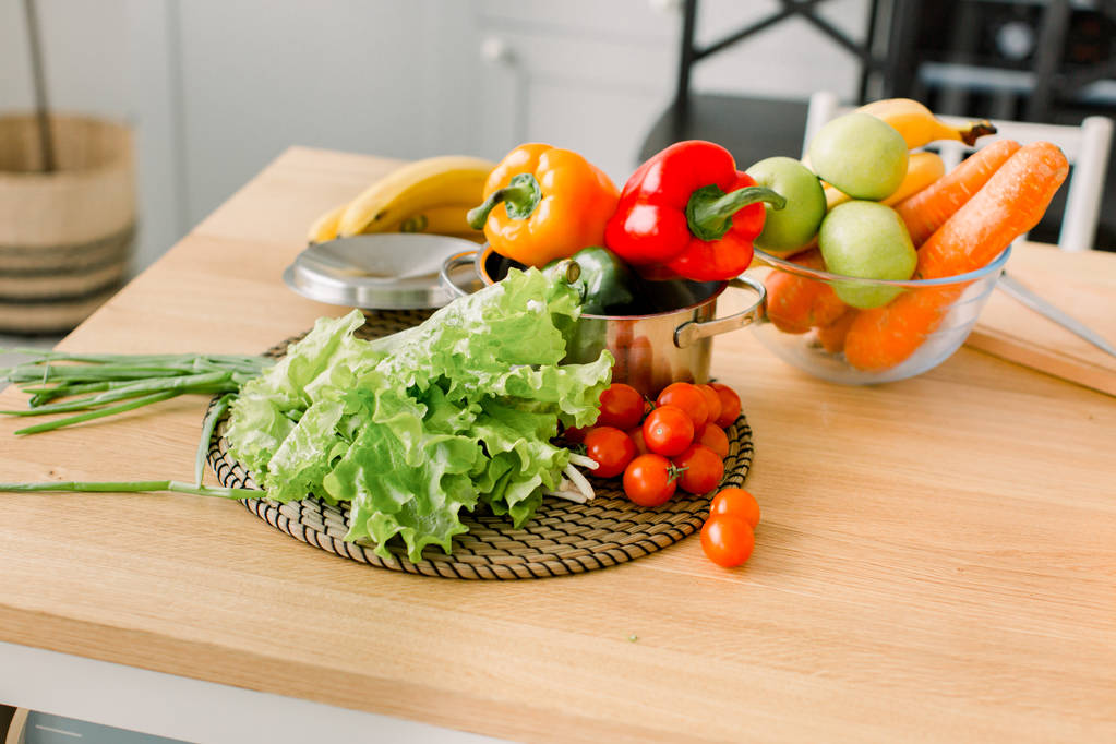 υγιεινά τρόφιμα είναι στο τραπέζι στην κουζίνα στο σπίτι. Φρέσκα λαχανικά και σκεύη για μαγείρεμα στο ξύλινο τραπέζι. Υγιεινά τρόφιμα, μαγειρική έννοια - Φωτογραφία, εικόνα