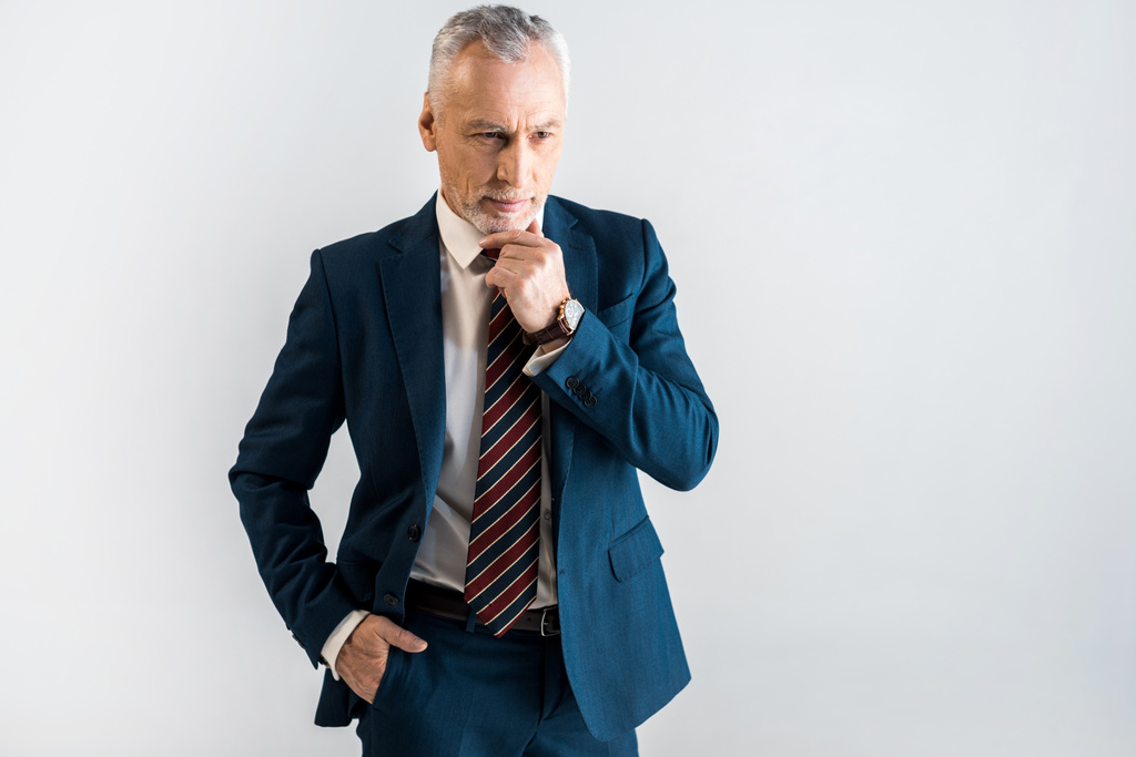 стомлений зрілий бізнесмен у костюмі, що стоїть з рукою в кишені ізольовано на сірому
  - Фото, зображення