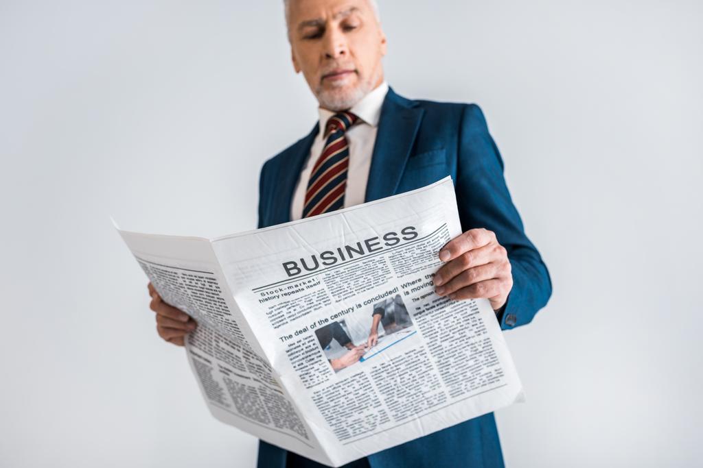グレーに分離されたビジネス新聞を読む中高年ビジネスマンの選択と集中  - 写真・画像
