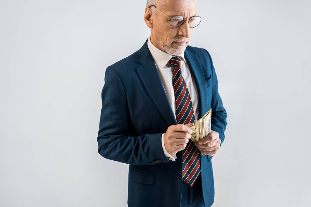 vista aerea di uomo maturo in occhiali e abbigliamento formale in possesso di banconote in dollari isolato su grigio
  - Foto, immagini