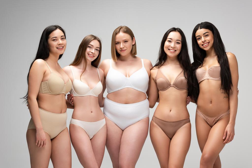 пять красивых мультикультурных девушек в нижнем белье, смотрящих в камеру и улыбающихся изолированно на сером, концепция позитивности тела
 - Фото, изображение