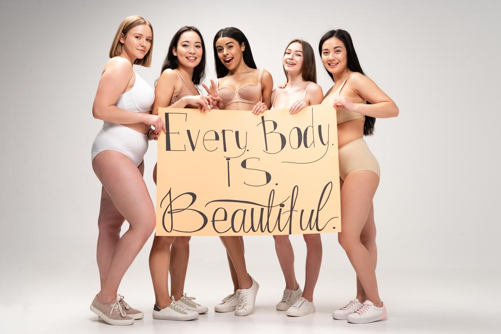 cinque allegre ragazze multietniche che tengono cartello con scritte "ogni corpo è bello"
  - Foto, immagini