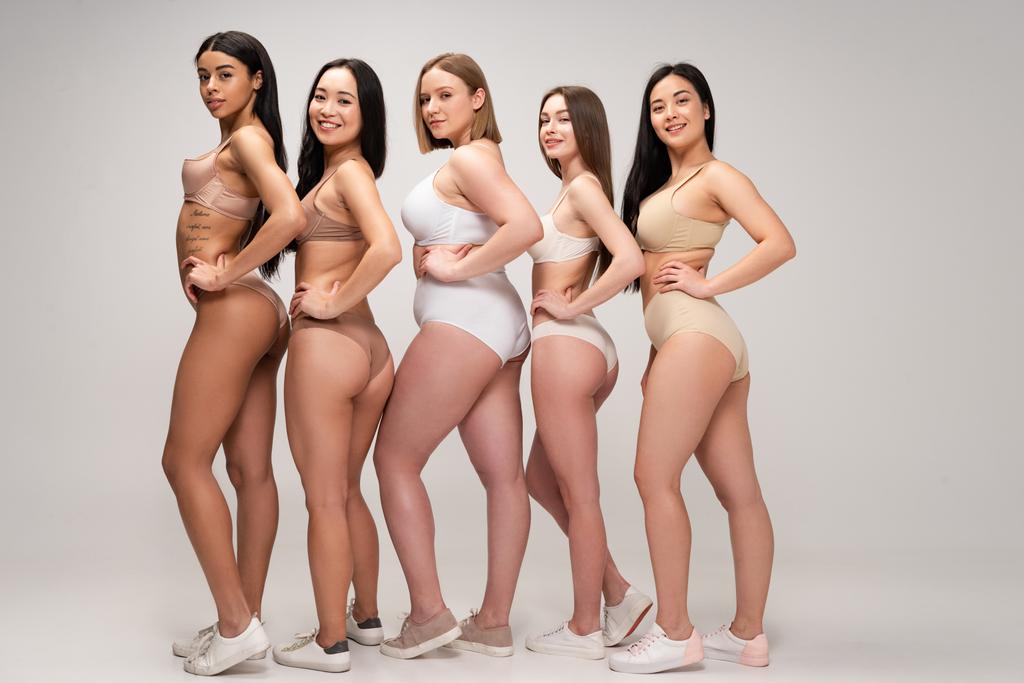 vijf jonge multi-etnisch vrouwen in lingerie poseren met de handen op de heupen, body positiviteit concept - Foto, afbeelding