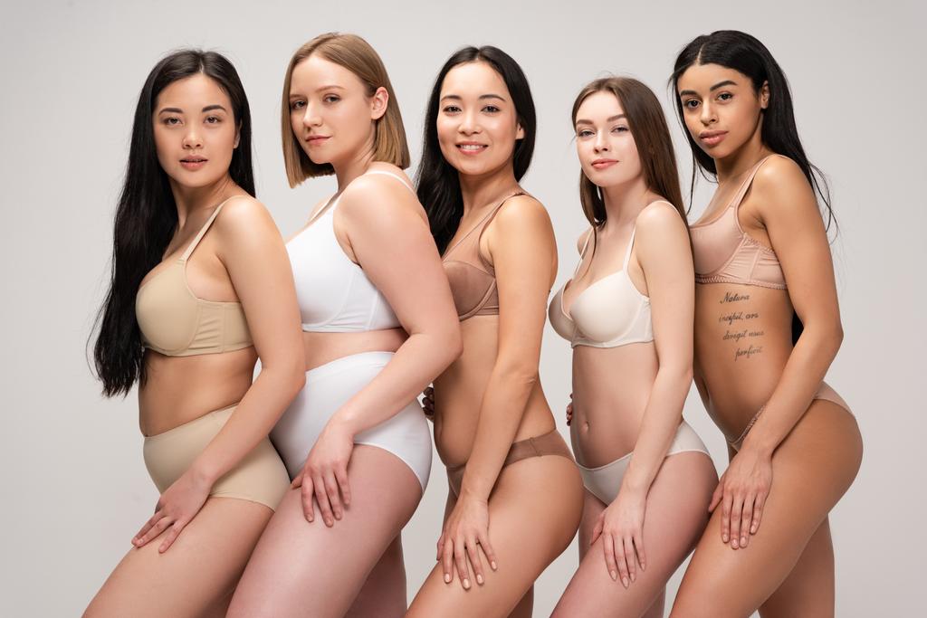 pięciu atrakcyjnych dziewczyn wielokulturowym w bieliźnie, pozowanie na kamery i uśmiecha się na białym tle na szary, ciało pozytywności koncepcja  - Zdjęcie, obraz