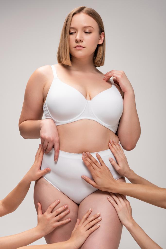 обрезанный вид женских рук, касающихся довольно толстой девушки, изолированной на сером, концепция положительности тела
 - Фото, изображение