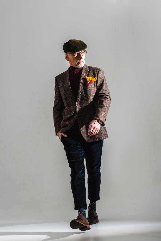 trendikäs keski-ikäinen mies lasit ja korkki kävely käsi taskussa harmaa
  - Valokuva, kuva