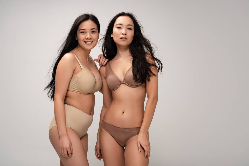 twee vrij multi-etnisch meisjes in ondergoed kijken camera geïsoleerd op grijs, lichaam positiviteit concept - Foto, afbeelding