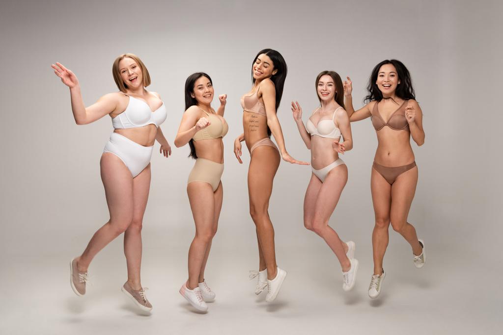 five pretty multicultural girls in lingerie having fun and jumping, body positivity concept - Photo, Image