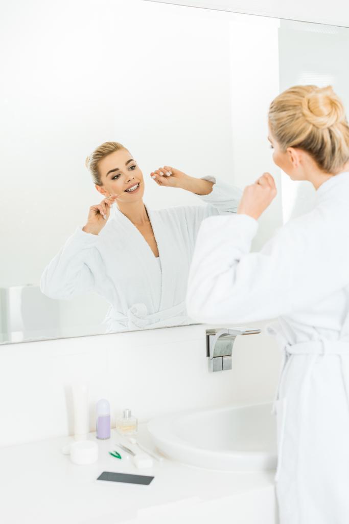 foyer sélectif de belle femme blonde en peignoir blanc brossant les dents avec fil dentaire
 - Photo, image