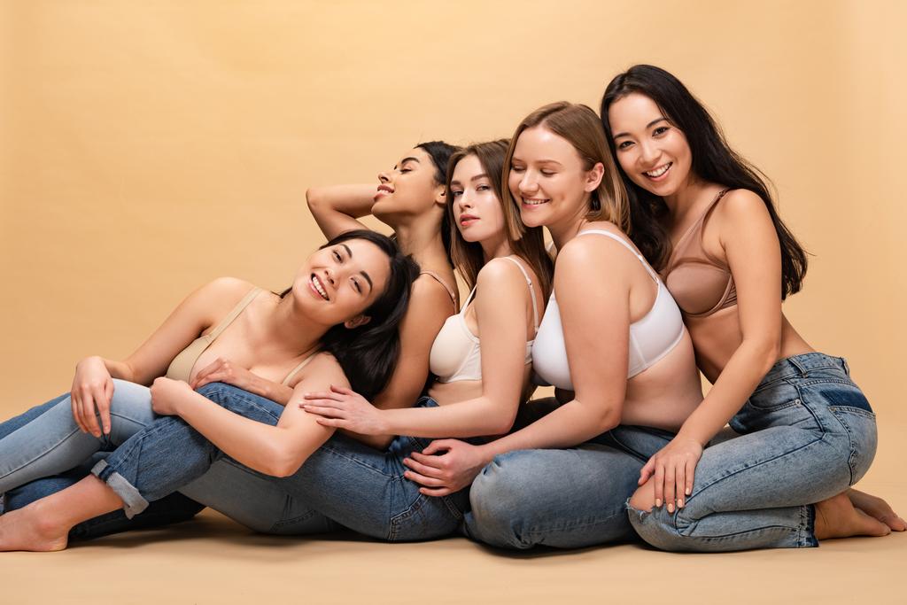 five smiling multicultural women sitting together and leaning on each other, body positivity concept - Photo, Image