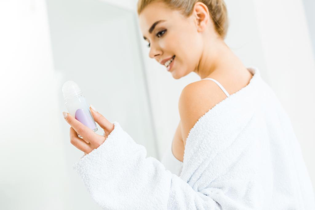ブラジャーと浴室の消臭剤を保持しているバスローブで美しい女性の選択と集中  - 写真・画像