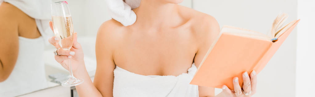 panoramique de la femme en serviette tenant champagne livre de lecture en verre dans la salle de bain
  - Photo, image
