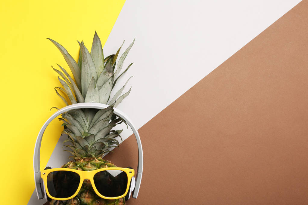 Lustige Ananas mit Kopfhörer und Sonnenbrille auf farbigem Hintergrund, Draufsicht. Raum für Text - Foto, Bild