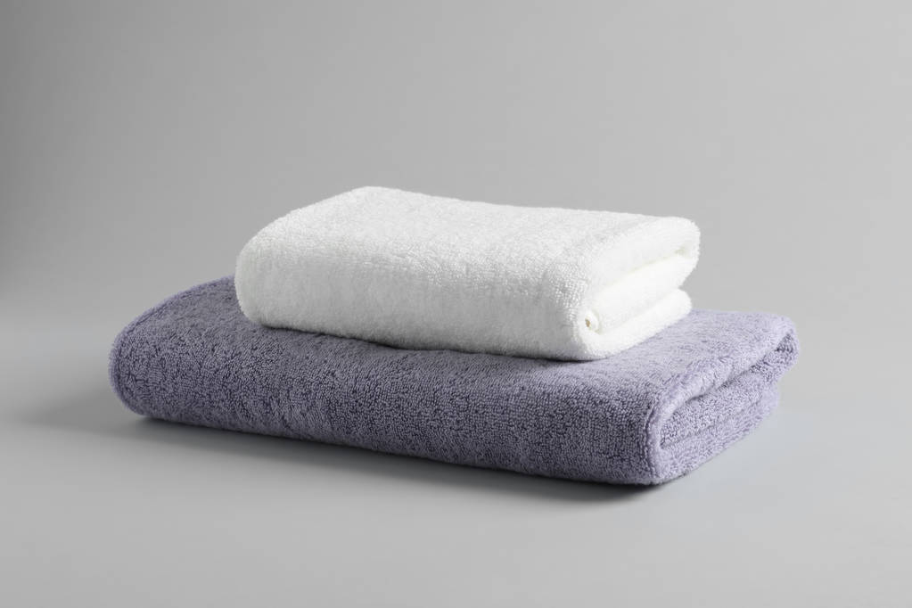 Στοίβα από φρέσκο αφράτες πετσέτες σε γκρίζο φόντο - Φωτογραφία, εικόνα
