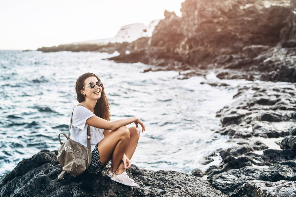 Piuttosto lunghi capelli ragazza turistica rilassante sulle pietre vicino al mare
. - Foto, immagini