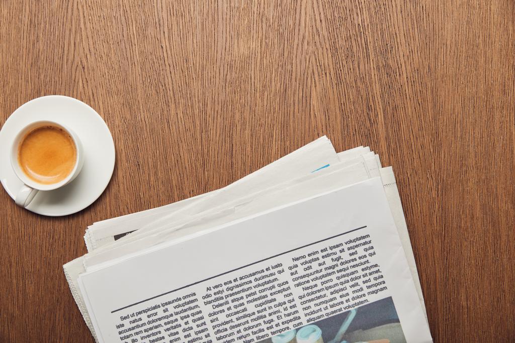top view of newspaper near cup of coffee on wooden surface  - Photo, Image