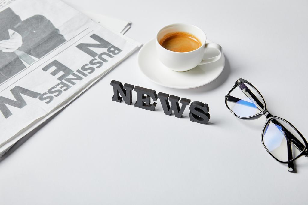 news lettering near cup of coffee, glasses and business newspaper on white  - Photo, Image