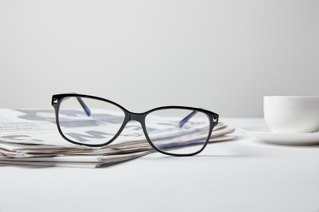selective focus of glasses near business newspaper and cup on white  - Photo, Image