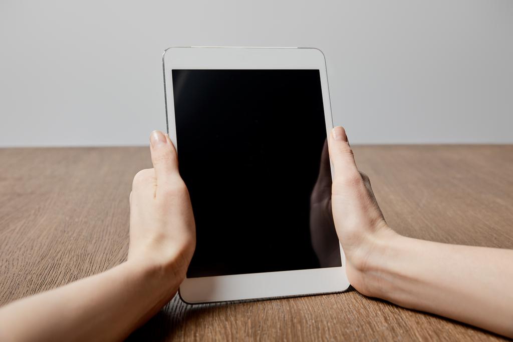 обрезанный вид женщины с помощью цифрового планшета с чистым экраном возле деревянной поверхности
  - Фото, изображение