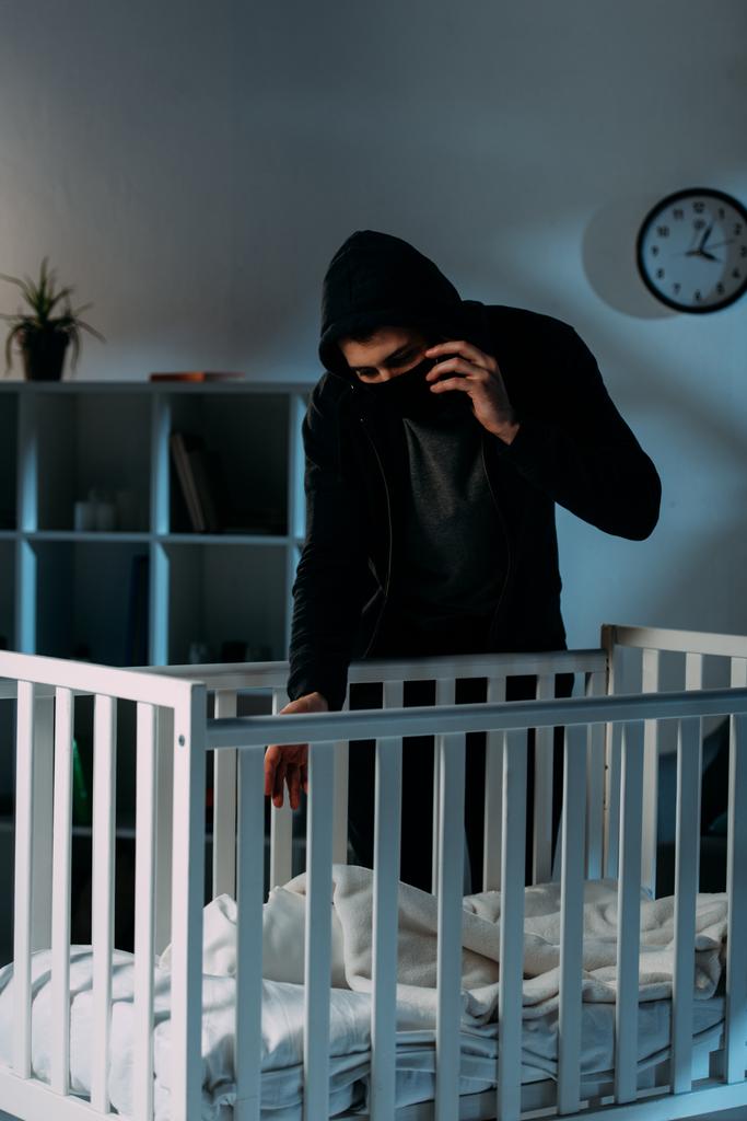 Преступник в маске разговаривает по смартфону во время похищения ребенка
 - Фото, изображение