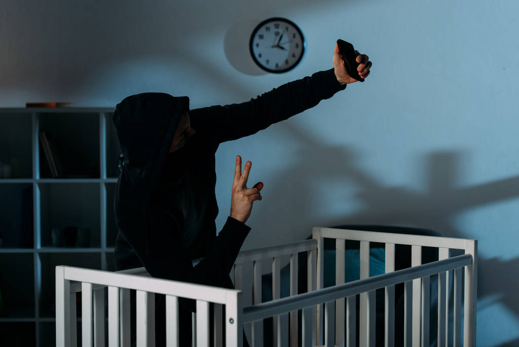 Rapitore prendendo selfie vicino culla e mostrando segno di pace
 - Foto, immagini