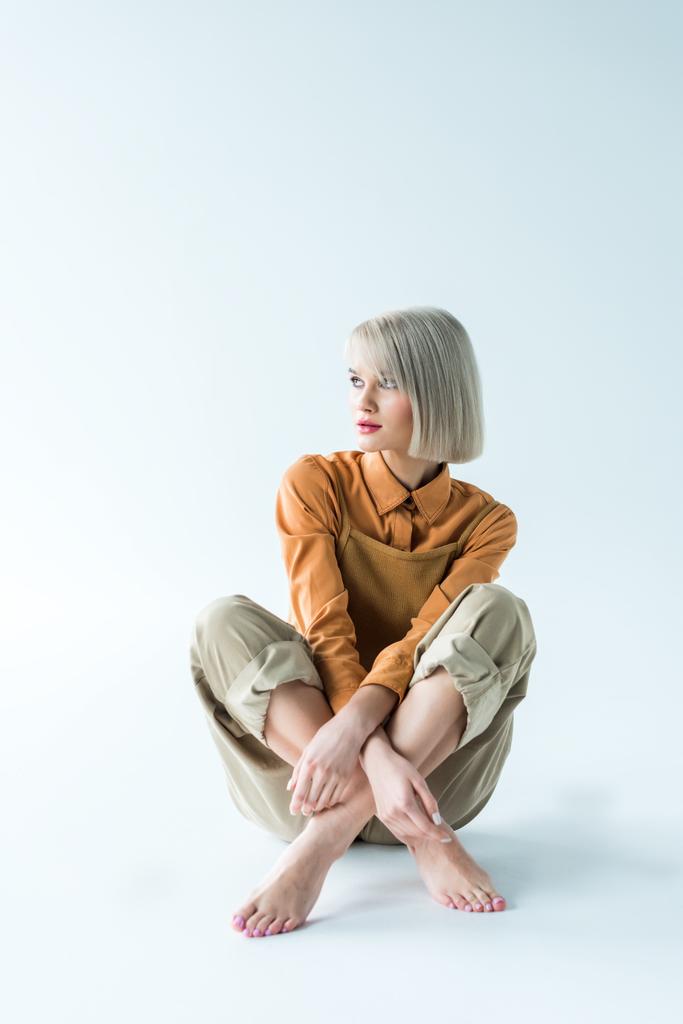 mooie stijlvolle jongedame zitten met gekruiste benen op wit  - Foto, afbeelding